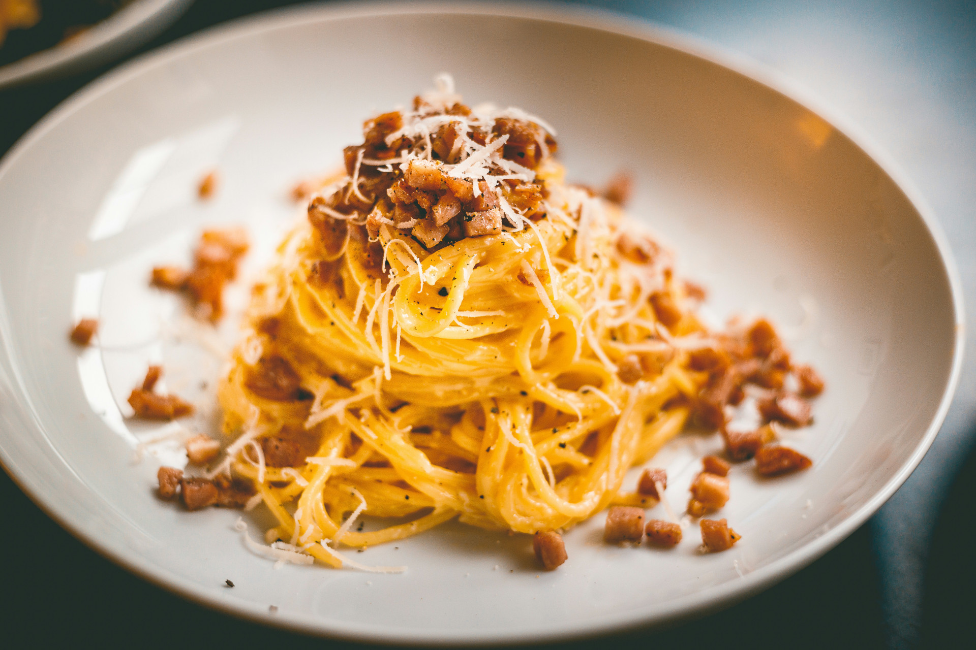 Close-up angle of a plate of spaghetti alla carbonara garnished with pecorino cheese